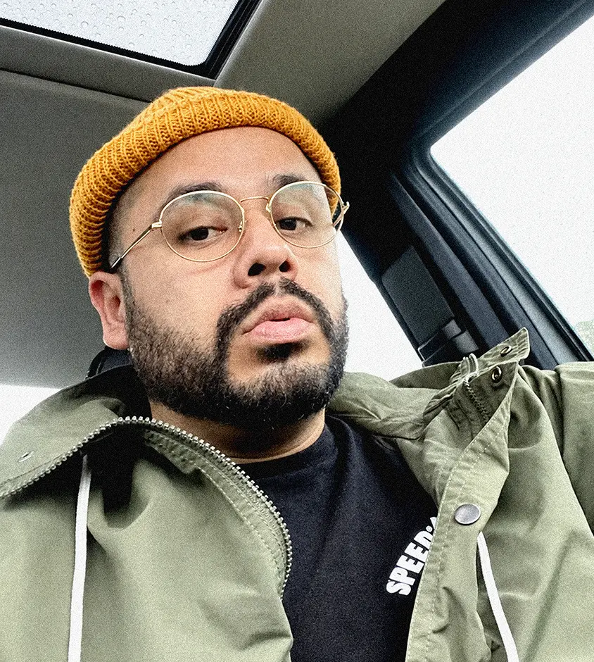 Marcos Moreno in a mustard beanie and round glasses